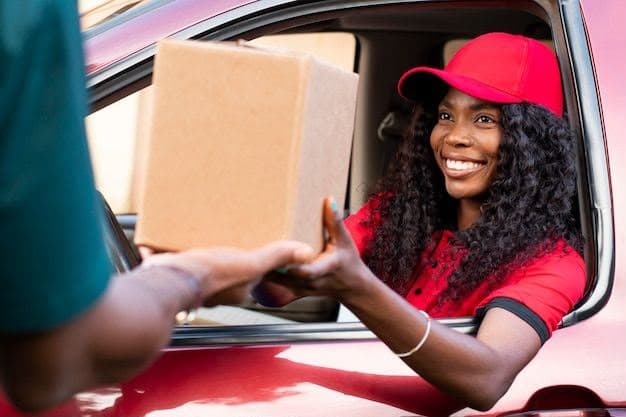 Une cliente souriante reçoit son colis par la fenêtre de sa voiture